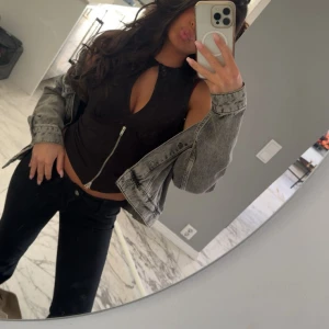 Svart croppad topp med dragkedja - Säljer en svart croppad topp med cool cut-out framtill och sned dragkedja. Toppen är ärmlös och har en tight passform som framhäver figuren. Perfekt för dig som gillar trendiga detaljer och vill sticka ut. Använd en gång!! Skriv för mer bilder.