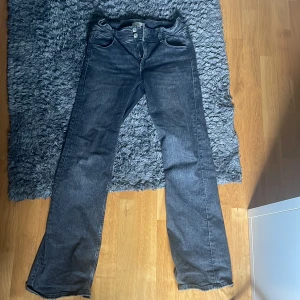 Svarta bootcut jeans Gina Young - Mörkblå jeans från Gina Tricot i klassisk bootcut-modell. Jeansen har två knappar framtill, dragkedja och fickor både fram och bak med lock och knapp. Materialet är jeans med lätt tvättad look. Dem är lite sönder där nere som man ser på bilderna. Skriv om ni har några frågor eller vill ha någon bild!💘