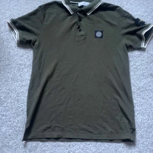 Olivgrön Stone Island pikétröja - Snygg olivgrön piké från Stone Island med klassisk logga på bröstet och ärmen. Helt ny storlek S men passar även M