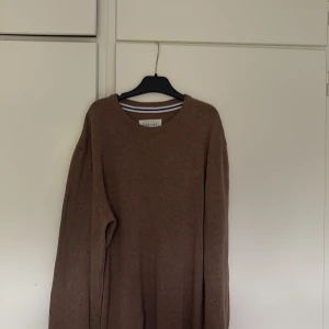 Brun stickad tröja från Pier One - En stilren brun stickad tröja från Pier One med rund halsringning och långa ärmar. Perfekt för lager-på-lager och enkel att matcha med jeans eller chinos. Tröjan har en klassisk passform och är supermjuk mot huden. Tröjan är i storlek S, använd cirka 3 tillfällen 