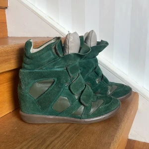 Gröna Isabel Marant sneakers med kilklack - Jag säljer ett par gröna Isabel Marant skor med kilklack. Skorna har en mix av mocka och skinn. Skorna är sååå fina men tyvärr lite stora för mig. Jag skulle säga att det är en stor storlek 37 men kanske tilloch med åt 38 hållet. Någonting däremellan. Även fast det är en hög klack är dom otroligt bekväma och man får inte ont i fötterna efter en hela dag av att gå i klackskor 😃