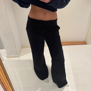 Svarta vida kostymbyxor - Säljer ett par svarta kostymbyxor med vid passform och klassisk look. Byxorna har normal midja och raka, vida ben som ger en chill och stilren vibe. Perfekta att styla med sneakers eller boots för en clean outfit.