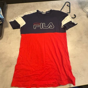 FILA t-shirt med logoband och färgblock - Cool t-shirt från FILA med färgblock i marinblått, rött och vitt. Stort FILA-tryck på bröstet och logoband längs axlarna. Kortärmad och tillverkad i mjuk bomull. Perfekt för dig som gillar sportig och street-inspirerad stil.