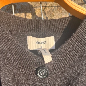 Svart stickad kofta från OBJECT – storlek S - Superfin svart kofta från OBJECT i storlek S. Klassisk modell med knappar hela vägen och ribbade kanter vid ärmar och midja. Perfekt basplagg att styla både till vardags och fest