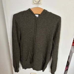 Olivgrön kashmirhoodie John Henric M - Mjuk olivgrön hoodie i 100% kashmir från John Henric. Tröjan har huva, lång ärm och känguruficka framtill. Perfekt för dig som gillar en clean och stilren look med lyxig känsla. Passformen är normal och materialet är supermjukt mot huden. Använt få antal gånger. Nypris 2600