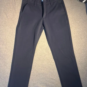 Midnattsblå kostymbyxor från Grunt - Snygga midnattsblå kostymbyxor från Grunt i modellen Dude Pant. Byxorna har raka ben, klassiska fickor och stängs med dragkedja och knapp. Perfekta för en clean och stilren look. Materialet känns mjukt och följsamt.