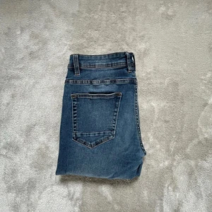 Blå jeans från Smog/Denim, 31/32 - Snygga blå jeans från Smog/Denim i klassisk femficksmodell. Jeansen har normal passform och raka ben, med kontrastsömmar och bälteshällor. Perfekta till vardags för en avslappnad stil. Tillverkade i slitstarkt denim-material.