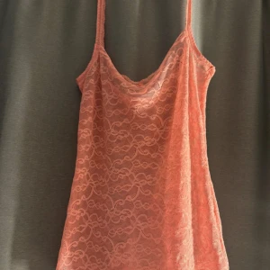 Rosa spetslinne från Intimissimi - Säljer en söt rosa från Intimissimi med tunna axelband och vacker spets över hela plagget. Linnet är ärmlös och har ett romantiskt mönster i spetsen som ger en feminin vibe. Perfekt för dig som gillar mjuka färger och detaljer.