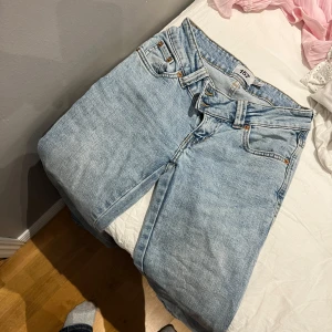 Ljusblå jeans med broderade fickor - Säljer ett par ljusblå jeans från 157 med snygga guldiga broderier på bakfickorna. Klassisk femficksmodell med raka ben och normal passform. Jeansen har en cool vintage vibe och är tillverkade i mjukt denimtyg. Perfekt för dig som gillar detaljer och vill sticka ut.