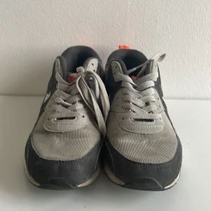 Nike Air Max sneakers  - Nike Air Max sneakers i grått och svart med orange detaljer och reflekterande silvrig swoosh. Ovandel i mesh och syntet, klassisk Air Max-sula och snörning. Perfekt för dig som gillar streetstyle och sportig vibe. Obs skorna tvättas innan de skickas.