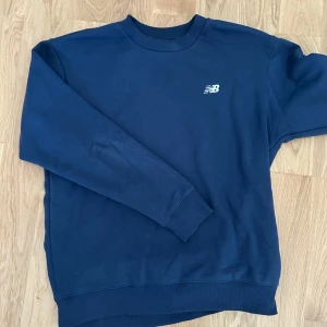 Mörkblå sweatshirt från New Balance - Mörkblå sweatshirt från New Balance med klassisk rund hals och diskret NB-logga broderad på bröstet. Riktigt varm och skön och väldigt bra passform. Snygg färg och mycket bra skick