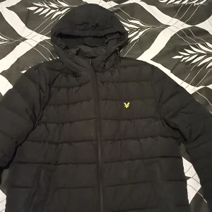 Svart pufferjacka från Lyle & Scott - Säljer min Lyle&Scott jacka för att den inte kommer till användning. Den finns en liten repa på framsidan bredvid dragkedjan men den påverkar inte jackans funktion på något sätt och man ser den knappt.Pris kan diskuteras!!!