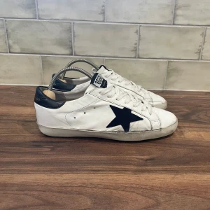 Golden Goose Sneakers  - Golden Goose Skor | Skicket är 6,5/10 - Storlek 41(Passar till 42) - Nypris 5599kr -Vårt pris 999kr,skorna är i bra skick, har defekter på sulan, även lite missfärgningar och sliten på skosnörena, lite sönder även vid hälen .Ingår endast sk