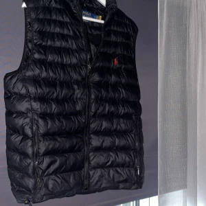 Svart dunväst från Polo Ralph Lauren - Säljer en svart dunväst från Polo Ralph Lauren i storlek M. Har inte använt den så mycket så den är i bra skick. Nypris ligger runt 3300