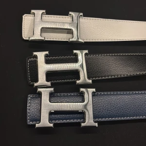 Bälte med stor H-spänne - Snygga bälten med stort H-format metallspänne. Finns i tre färger: vitt, svart och mörkblått. Bältena har en stilren design med synliga sömmar längs kanterna och är tillverkade i skinn. Du kan få en för 200 eller alla för 500