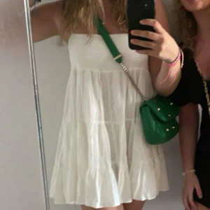 Vit volangklänning - Säljer en söt vit klänning med volanger och lös passform. Klänningen är ärmlös och har en luftig känsla, perfekt för varma dagar. Enkel och stilren design som passar till många tillfällen.
