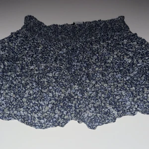 Blommig kjol från KappAhl - Söt blommig kjol från KappAhl i blå och vita nyanser. Kjolen har en elastisk midja för en bekväm passform och är perfekt för varmare dagar. Den korta längden ger en ungdomlig och fräsch look.