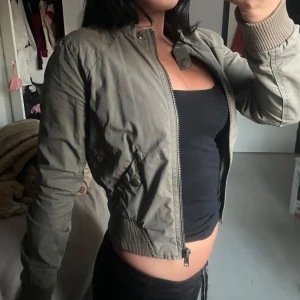 Beige bomberjacka - Intressekoll Snygg beige bomberjacka med dragkedja och ribbade muddar. Jackan har en kort passform och är perfekt för en casual look. Den har långa ärmar och en stilren design.