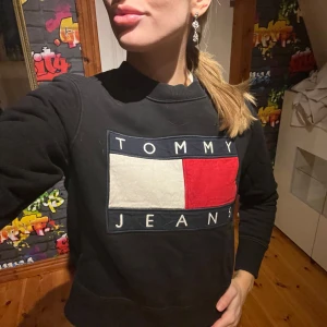 Svart sweatshirt från Tommy Jeans - Säljer en svart sweatshirt från Tommy Jeans med stor logga framtill. Säljer då den inte används. 