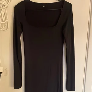 Svart långklänning med lång ärm - En stilren svart långklänning med lång ärm och figurnära passform. Perfekt för dig som gillar minimalistisk och tidlös stil. Klänningen har rund halsringning och är tillverkad i ett stretchigt material som sitter snyggt på kroppen. Klänningen går ända ner till fötterna