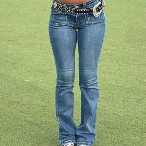 Blå bootcut jeans med låg midja - Snygga blå jeans med bootcut-passform och låg midja. Klassisk femficksmodell med markerade sömmar och lätt tvättad look. Perfekta för en avslappnad stil och passar till många olika outfits. (Den kommer utan bältet)