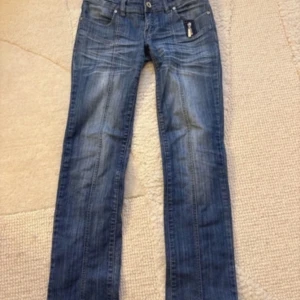 Unika lågmidjade raka jeans - Unika lågmidjade raka jeans med dragkedjedetaljer. W28, passar som en XS/S. Midjemått 37 cm, Innerbenslängd 82cm