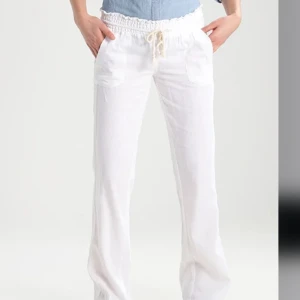 Roxy Vita linnebyxor  - Säljer ett par vita linnebyxor med resår och dragsko i midjan. Byxorna har raka ben, fickor fram och bak samt en avslappnad passform. Perfekta för varma dagar och enkel att matcha med olika toppar. Dem skulle bara behövas strykas så ser dem perfekt ut 