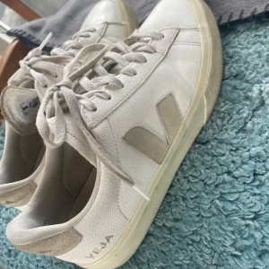 Vita sneakers från Veja - Snygga vita sneakers från Veja med klassisk design och snörning. Skorna har en diskret logga på sidan och hälpartiet. Perfekta för en stilren look. Skorna är använda men i bra skick och storlek 40!💞