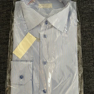 Blåvit randig skjorta från Eton - Klassisk skjorta från Eton i blåvitt randigt mönster. Skjortan har lång ärm, knappar framtill och klassisk krage. Perfekt för en stilren och dressad look. Tillverkad i bomull för en skön känsla.