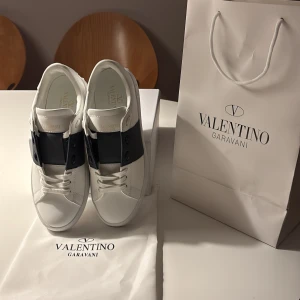 Valentino skor open  - Säljer ett par vita Valentino Garavani Open sneakers med en bred blå läderdetalj över mitten. Skorna är endast testade på men var för stora därav säljer jag. Storlek 43. Hör av er vid minsta intresse🌟🤩