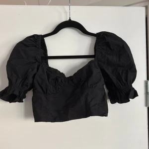 Svart blus  - Snygg svart blus med puffiga korta ärmar och en croppad design. Har ej lappen kvar men är säker på att de är storlek xs/34