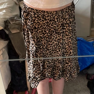 Leopardmönstrad kjol från Lindex - Säljer en snygg leopardmönstrad kjol från Lindex i beige och svart. Kjolen har volangdetaljer och knytband i midjan. riktigt snyggt till sommaren säljer på grund av storlek