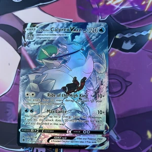 Pokémonkort Ice Rider Calyrex VMAX - Säljer ett holografiskt Pokémonkort: Ice Rider Calyrex VMAX med 320 HP. Kortet har färgstark design med blå, vit och grön färg, samt glittrig yta. Text på engelska och illustration av Calyrex på en ishäst. Perfekt för samlare eller Pokémon TCG-spelare.