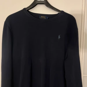 Mörkblå tröja från Polo Ralph Lauren - Säljer en klassisk mörkblå tröja från Polo Ralph Lauren med bomulls matrial. Tröjan har rund halsringning och diskret broderad logga på bröstet. Perfekt för en stilren och enkel look. Står strlk L men passar M