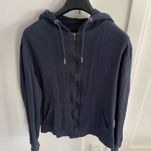 Mörkblå hoodie från 157 - Tja! Säljer en mörkblå hoodie från 157 i storlek M. Den har en dragkedja framtill och en justerbar huva med snören. Perfekt för en avslappnad stil. Hör av dig vid intresse eller vid funderingar!