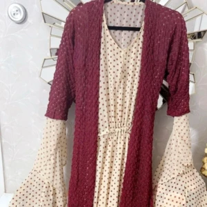 Vinröd och cremeprickig kurdisk klänning - Unik kurdisk klänning  i vinrött och creme med prickigt mönster. Klänningen har vida, volangiga ärmar i cremefärgat tyg med vinröda prickar och en smockad vinröd överdel. V-ringad hals och markerad midja för snygg siluett. Klänningen är passar storleken S och M✨