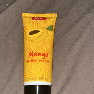 XBC Mango Body Wash 100ml - Fräsch duschgel med söt mangodoft från XBC. Kommer i en smidig gul tub med tropiskt mönster och mangomotiv. Perfekt för dig som vill ha en exotisk känsla i duschen. Innehåller 100 ml.