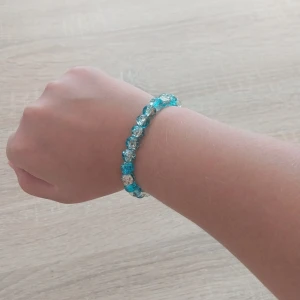 Blått och transparent pärlarmband - Ett snyggt armband med runda pärlor i blått och transparent. Pärlorna har en glittrig effekt som fångar ljuset och ger en cool vibe. Perfekt accessoar för att lyfta din outfit med lite färg och bling.