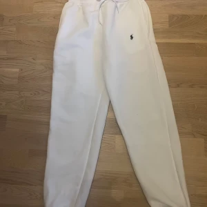 Vita mjukisbyxor Polo Ralph Lauren - Snygga vita mjukisbyxor från Polo Ralph Lauren med klassisk broderad logga på benet. Byxorna har resår och snörning i midjan samt mjukt material som känns skönt mot huden. Perfekta för chill dagar eller när du vill ha en clean look.
