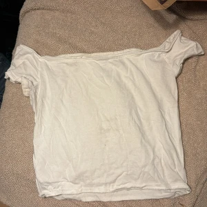 Vit offshoulder topp från H&M - Säljer en enkel och stilren vit offshoulder topp från H&M. Toppen är ärmlös med bred halsringning som sitter snyggt över axlarna. Tillverkad i mjuk bomull, perfekt för en avslappnad look. Passar dig som gillar minimalistisk stil.