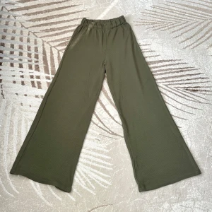 Klädpaket - Wide ribbade byxor i olivgrönt & vinrött - Bekväma och snygga byxor i ribbat tyg. Ett par i vinrött och ett par i olivgrönt. Båda med hög midja och vida ben – perfekta för vardagsbruk eller användning som pyjamas.  Storlek: M  Material: 95% bomull, 5% elastan – mjuka och stretchiga för extra komfort.  Säljes som paket.