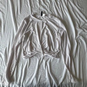 Vit ribbad croppad topp H&M Divided - Säljer en vit långärmad topp från H&M Divided i storlek L. Toppen är ribbad, croppad och har en snygg twistad detalj framtill. 