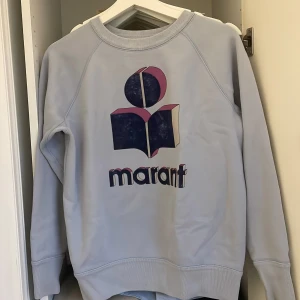 Ljusblå sweatshirt Isabel Marant - Säljer en ljusblå sweatshirt från Isabel Marant med stort tryck i blått och rosa framtill. Tröjan har rund hals, långa ärmar och ribbade muddar. Perfekt för alla outfits. Man kan ha den på vintern, våren, sommaren och hösten. Använd ett fåtal gånger, och är nästan i nyskick.