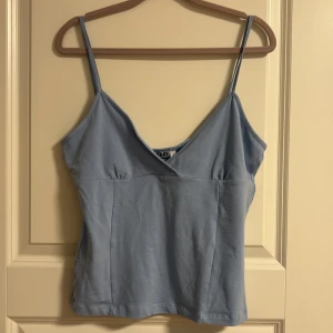 Ljusblå linnetopp från Weekday - Säljer en ljusblå linnetopp från Weekday som jag bara har provat hemma en gång den har smala axelband och v-ringning. Toppen är i mjuk bomull och har en enkel, stilren design som är perfekt för varma dagar. Passar som en M/S. Priset går att diskutera🩷🩷