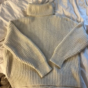 Beige stickad polotröja - Mysig beige stickad polotröja med grov ribbstickning och höga muddar. Tröjan har lång ärm och en rejäl polokrage som ger extra värme. Perfekt för kyliga dagar och enkel att styla med jeans eller kjol.