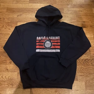 Saint Laurent hoodie  - Riktigt fet och eftertraktad hoodie med saint laurent loggan. Storlek M, skick 10/10!! Är lite osäker på äktheten så därför är priset just nu på 1199kr! Nypris runt 7000! Ser precis ut som originalet! Tveka inte med att ställa frågor!