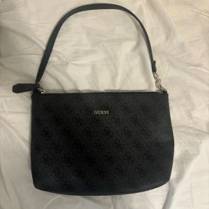 Svart axelväska från Guess - . Väskan har dragkedja upptill och insidan är fodrad med leopardmönster.  Skriv för mer info 