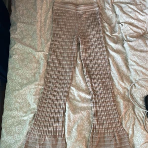 Beigea rutiga ribbade byxor - Säljer ett par beigea ribbade byxor med rutigt mönster och. Byxorna har hög midja och är stretchiga, perfekta för en chill och trendig look.