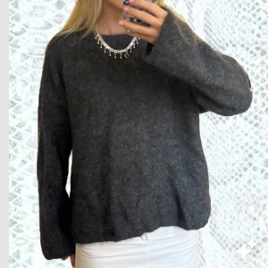 Mörkgrå stickad tröja i ullmix mohairmix - Mysig mörkgrå stickad tröja med rund hals och lång ärm. Tröjan har en lite lösare passform och är gjord i en fluffig ullmix som känns både varm och skön. Perfekt att slänga på sig när det är kyligt ute. Nypris: 800kr använd fåtal gånger. 