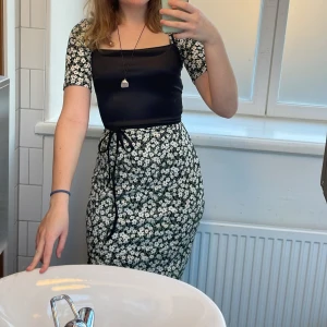 Blommig långklänning från Gina Tricot - Supersöt långklänning från Gina Tricot med svart botten och vita småblommor. Klänningen har halvkorta ärmar och figurnära passform. Perfekt för sommarens alla tillfällen och ger en romantisk vibe. * På den första bilden har jag en tröja över klänningen 